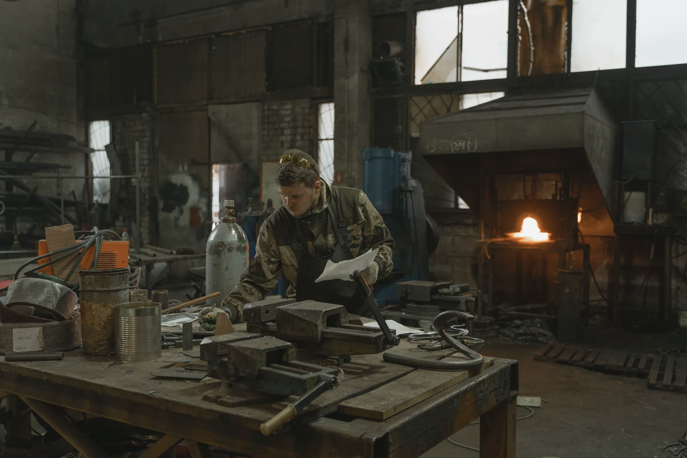 Metalworker reviewing plans at a workshop bench